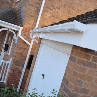 Close-up of a white gutter and doorway on a brick home exterior.