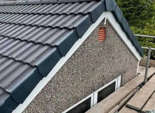 Roof section with grey tiles and textured walls, overlooking green foliage.